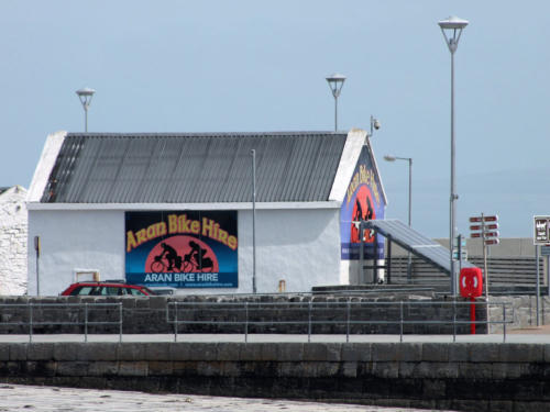 The Aran Bike Hire building on the pier, with a large sign showing cyclists