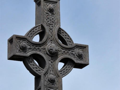 A carved stone Celtic cross against a blue sky