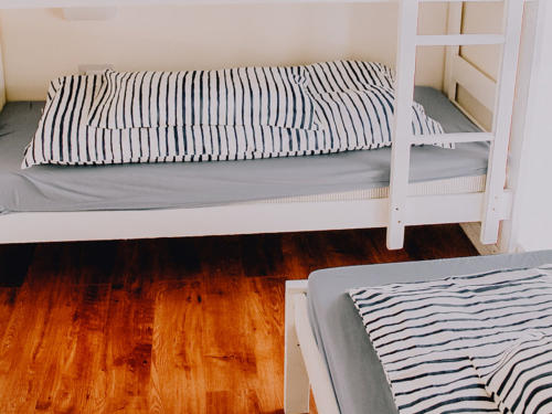A bunk bed with striped bedding and a grey mattress
