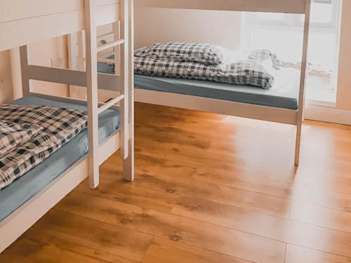 White bunk beds with checked bedding on a wooden floor