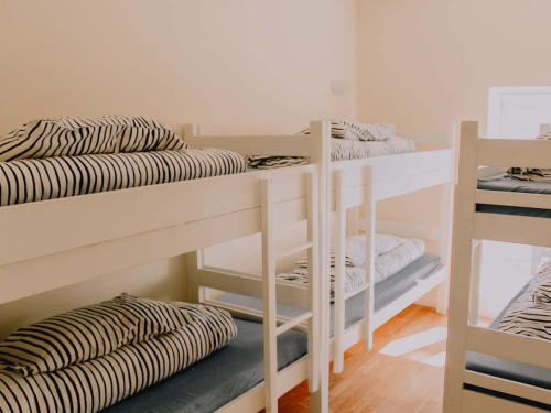 A dormitory with white wooden bunk beds and striped bedding