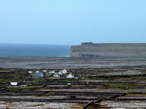 Small white houses and stone-walled fields below a headland on the island