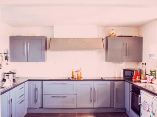 The hostel kitchen, with grey cabinets, an extractor hood and a hob