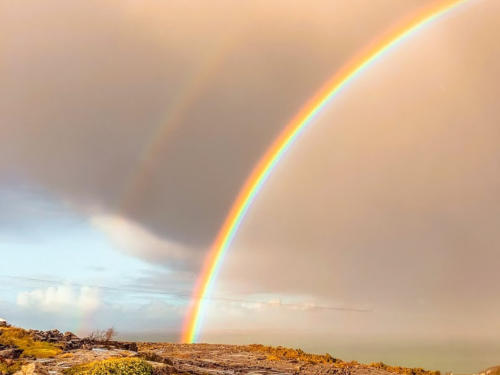 A rainbow arching over rocky limestone ground