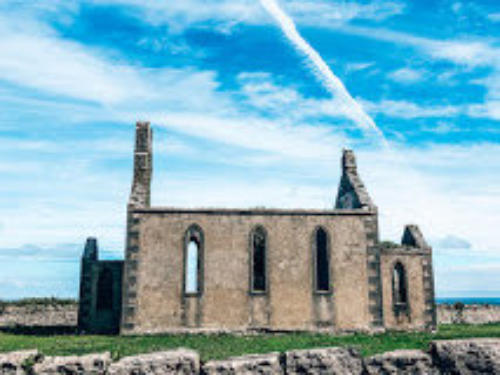 A ruined stone church with arched windows under a blue sky