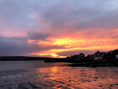 An orange and pink sunset over the harbour at low tide
