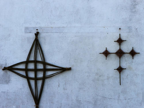 Two woven crosses hanging on a whitewashed wall